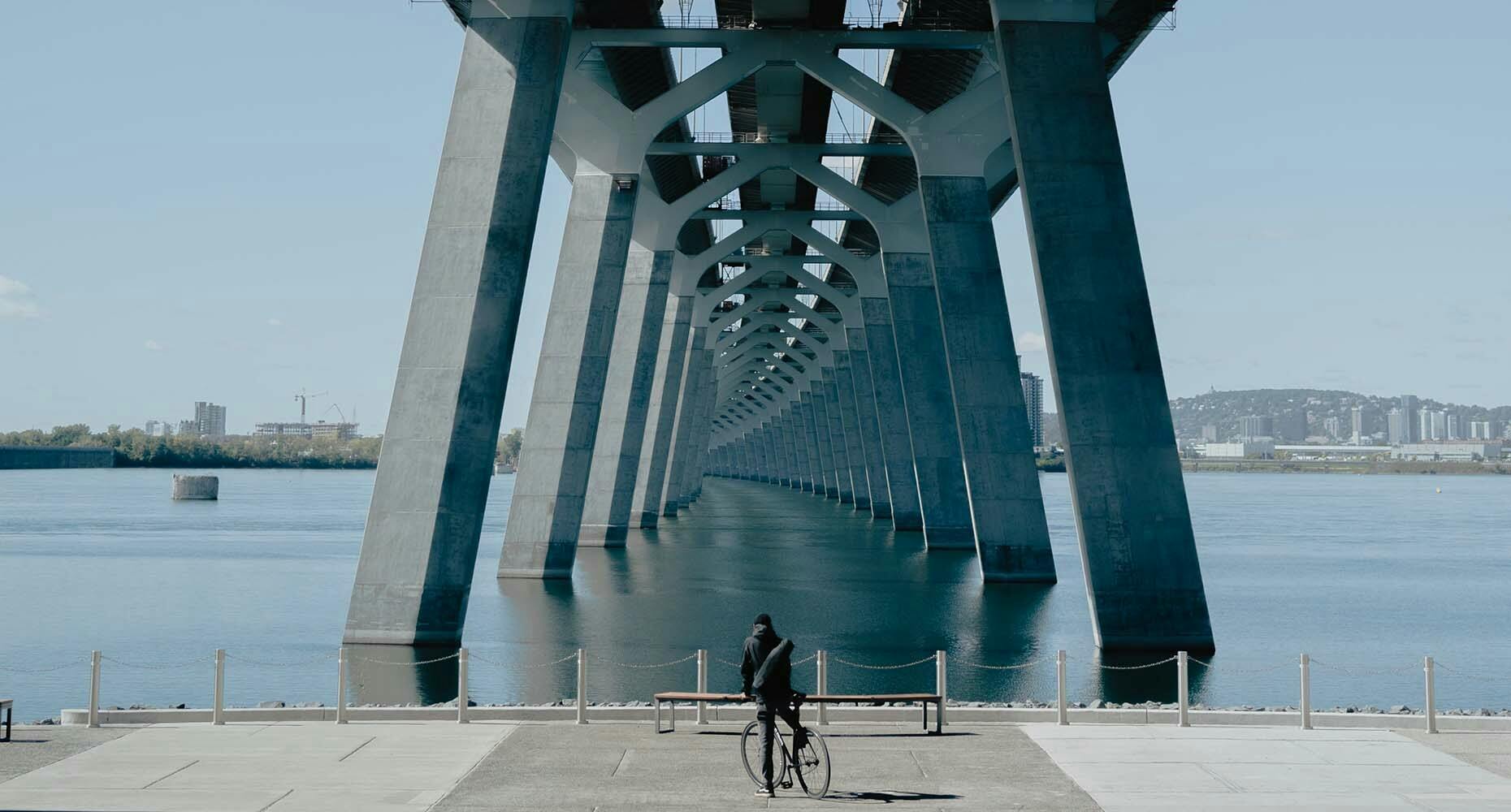 Biker underneath a bridge by the water