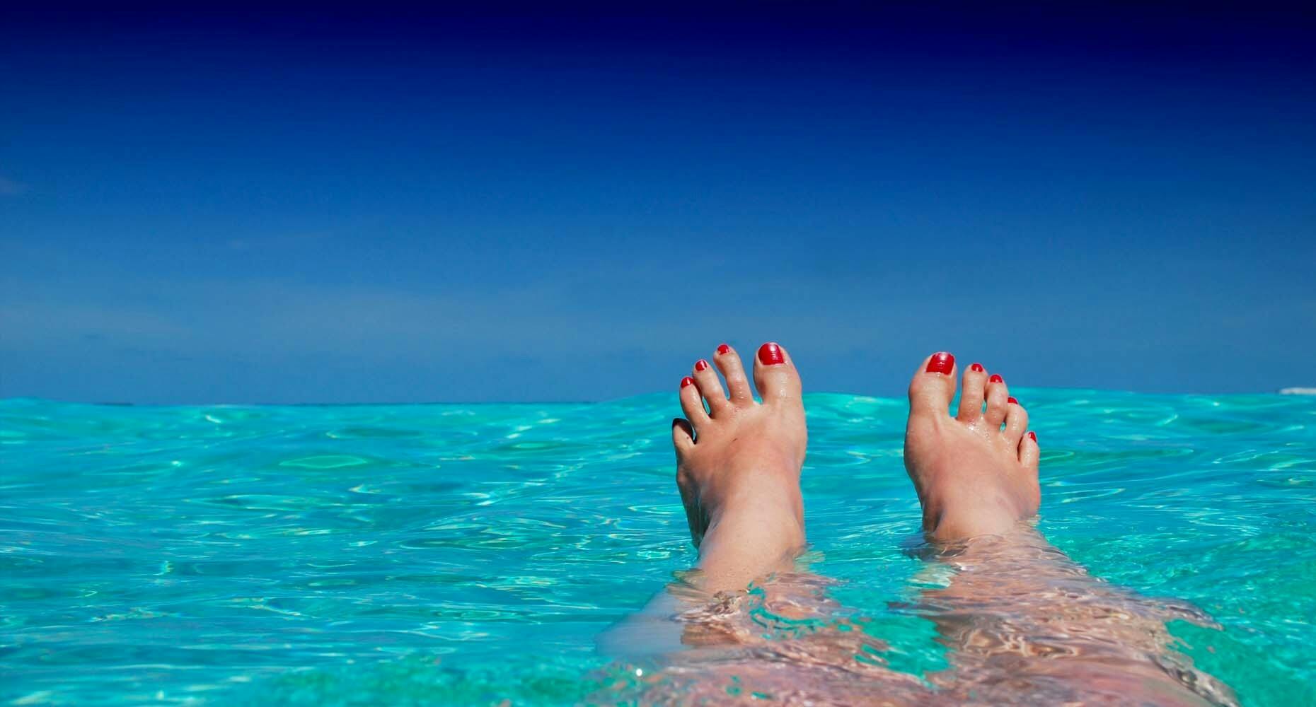 Feet on vacation in clear ocean